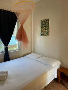 a bedroom with a white bed with a window at Christina's Guest House OFFICIAL in Little Corn Island