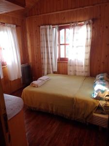 Un dormitorio con una cama y una ventana con cortinas. en Cabañas maiten, en El Maitén