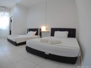 two beds in a room with white walls and white floors at Promenade Homestay 2 in Kampong Sura Masjid