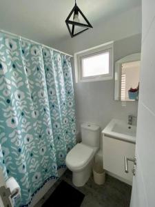 y baño con aseo, lavamanos y cortina de ducha. en Hermosa Casa El Tabo nueva en condominio, en El Tabo