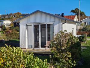 a small white house with a wooden deck at Minihuset nära havet in Varberg