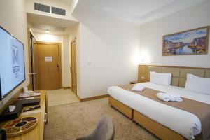 a hotel room with a bed and a flat screen tv at Milan Hotel in Tashkent