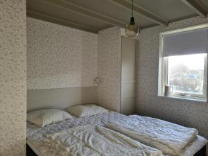 1 cama en un dormitorio con ventana en Minihuset nära havet en Varberg