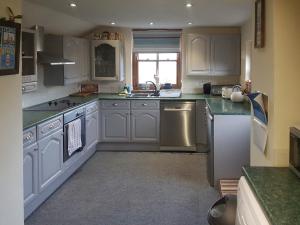 a kitchen with white cabinets and stainless steel appliances at Syke Cottage in Mickleton