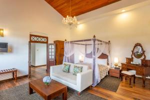 ein Schlafzimmer mit einem Himmelbett und einem weißen Sofa in der Unterkunft W15 Lake Gregory in Nuwara Eliya