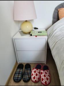 a bed with a side table with a lamp and a pair of shoes at Apartmani Nikolaj in Banja Koviljača