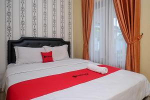 Una cama con una manta roja y blanca. en RedDoorz at Paris Ocean, en Yogyakarta