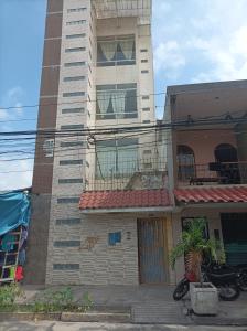 a tall building with a palm tree in front of it at Emmanuel&Cavita in Iquitos