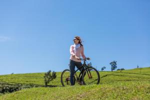 a woman riding a bike on a grassy hill at W15 Lake Gregory in Nuwara Eliya
