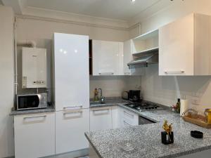 a kitchen with white cabinets and a microwave at LA PETITE PERLE A MARSA PLAGE in La Marsa