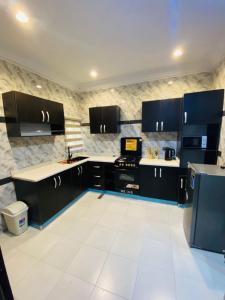 a kitchen with black cabinets and white tile floors at Officer Condo Apartments in Yanyan
