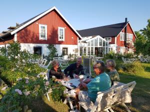 un grupo de personas sentadas alrededor de una mesa en un patio en Lanthotell Lögnäs Gård, en Laholm
