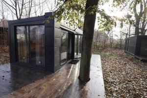a black cube house sitting next to a tree at Domki Hrabiego- domek nr 2 in Rozkochów