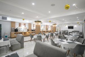 a restaurant with tables and chairs and a kitchen at Milan Hotel in Tashkent