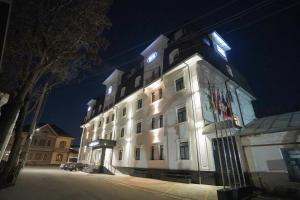 a large white building with a clock on it at night at Milan Hotel in Tashkent