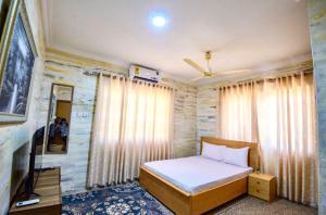 a bedroom with a bed and a large window at Bays Lodge - East Legon in Accra