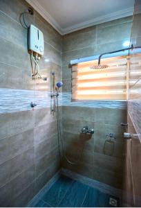 a bathroom with a shower with a glass door at Bays Lodge - East Legon in Accra