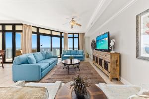 sala de estar con sofá azul y TV en The Oasis at Orange Beach 2203, en Orange Beach