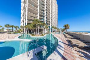 a swimming pool next to a building with palm trees at The Oasis at Orange Beach 2203 in Orange Beach