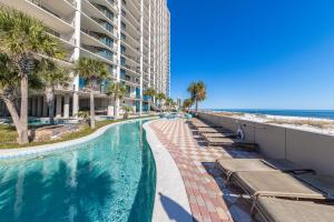 a swimming pool next to a beach and a building at The Oasis at Orange Beach 2203 in Orange Beach