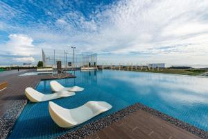 two white chairs sitting on the side of a swimming pool at Amber Cove Premier Suites Melaka in Melaka