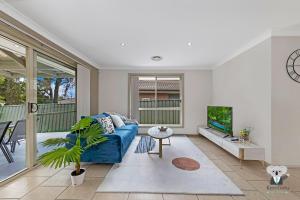 a living room with a blue couch and a tv at KozyGuru | Penrith | Cosy 4BED House | Free Internet in Penrith