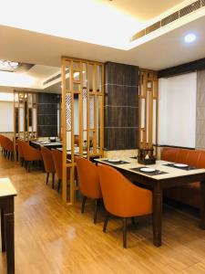 uma sala de jantar com mesas longas e cadeiras em Hotel Myriad em Lucknow