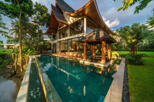 a house with a swimming pool in front of it at Villa Satiya - Unique and stylish 4-bdr pool villa in Pererenan! in Canggu