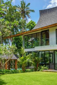 a house with large windows and a lawn at Villa Satiya - Unique and stylish 4-bdr pool villa in Pererenan! in Canggu