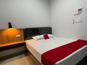 um pequeno quarto com uma cama com um cobertor vermelho em RedDoorz Plus near Alun Alun Kota Bora em Blora