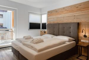 a bedroom with a large bed with a wooden wall at AvenidA Style Appartements by Alpin Rentals in Kaprun