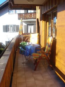 eine Terrasse mit einem Tisch, Stühlen und einem Sonnenschirm in der Unterkunft Landhaus Alpensee in Oberstdorf
