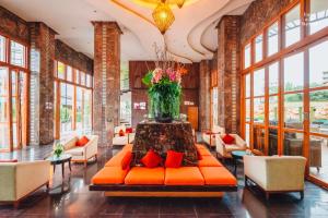 un vestíbulo con un sofá naranja y un jarrón de flores en Centara Nova Hotel Pattaya, en Pattaya central