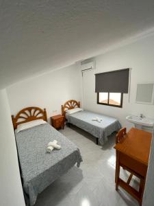 a hotel room with two beds and a table at Hostal La Campiña in Ronda