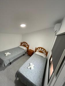 Habitación con 2 camas con cruces. en Hostal La Campiña en Ronda