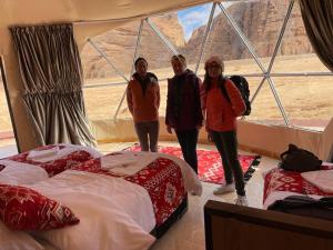 three women standing in a room with beds at مخيم الجبال البرونزية in Wadi Rum