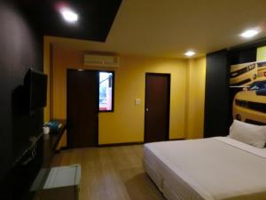a bedroom with a bed and a tv and yellow walls at NewYork Suite Hotel in Bangkok