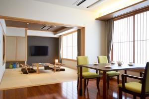 a living room with a table and chairs and a tv at Tendo Hotel in Tendo