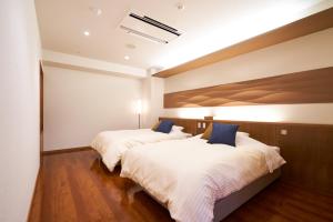 two beds in a hotel room with white sheets and blue pillows at Tendo Hotel in Tendo