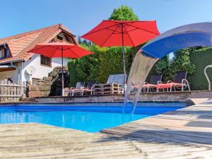 una piscina con una fuente de agua con sombrillas rojas en Grub-Daniel-Hof, en Freiamt