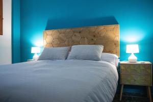 a bedroom with a large bed with blue walls and two lamps at Ático con terraza en Cuesta Gomérez in Granada