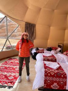 a woman standing in a room with two beds at مخيم الجبال البرونزية in Wadi Rum