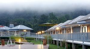 a house with an umbrella on a deck at Jeerang Countryside Resort in Mae Hong Son