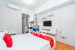 um quarto com uma cama branca com um cobertor vermelho em RedLiving Apartemen Green Lake View Ciputat - Mpo Yani Rooms Tower E with Fast Wifi em Tangerang