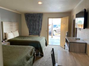 a hotel room with two beds and a sliding glass door at Antlers Budget Inn in Antlers