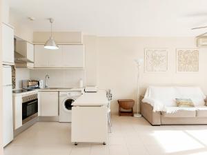 cocina blanca con sofá y mesa en Global Properties, Estudio Cerca de la Playa, Pet-friendly, en Canet de Berenguer