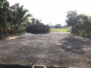 a gravel driveway with a gate in a field at Homestay Che Mat in Kuala Terengganu
