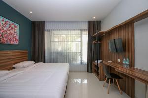 a bedroom with a bed and a desk and a television at TwoSpaces Living at Kencana Residence in Gunungsan