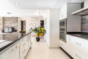 una cucina con mobili bianchi e ripiani neri di Playamar a Torremolinos