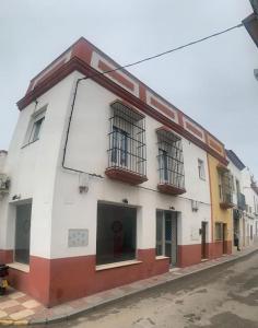 ein weißes und rotes Gebäude auf der Straßenseite in der Unterkunft Apartamento luminoso en Espartinas Totalmente climatizado in Espartinas